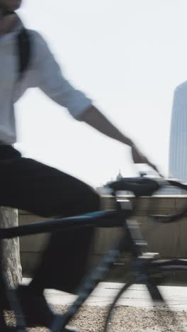 Vertical-Video-Cyclists-Commuting-Work-The-Embankment-City-Skyline-Background